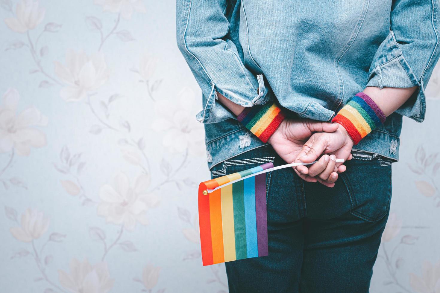 signora asiatica che indossa una giacca di jeans blu o una camicia di jeans e tiene in mano una bandiera color arcobaleno, simbolo del mese dell'orgoglio lgbt celebra l'annuale a giugno sociale di gay, lesbiche, bisessuali, transgender, diritti umani. foto