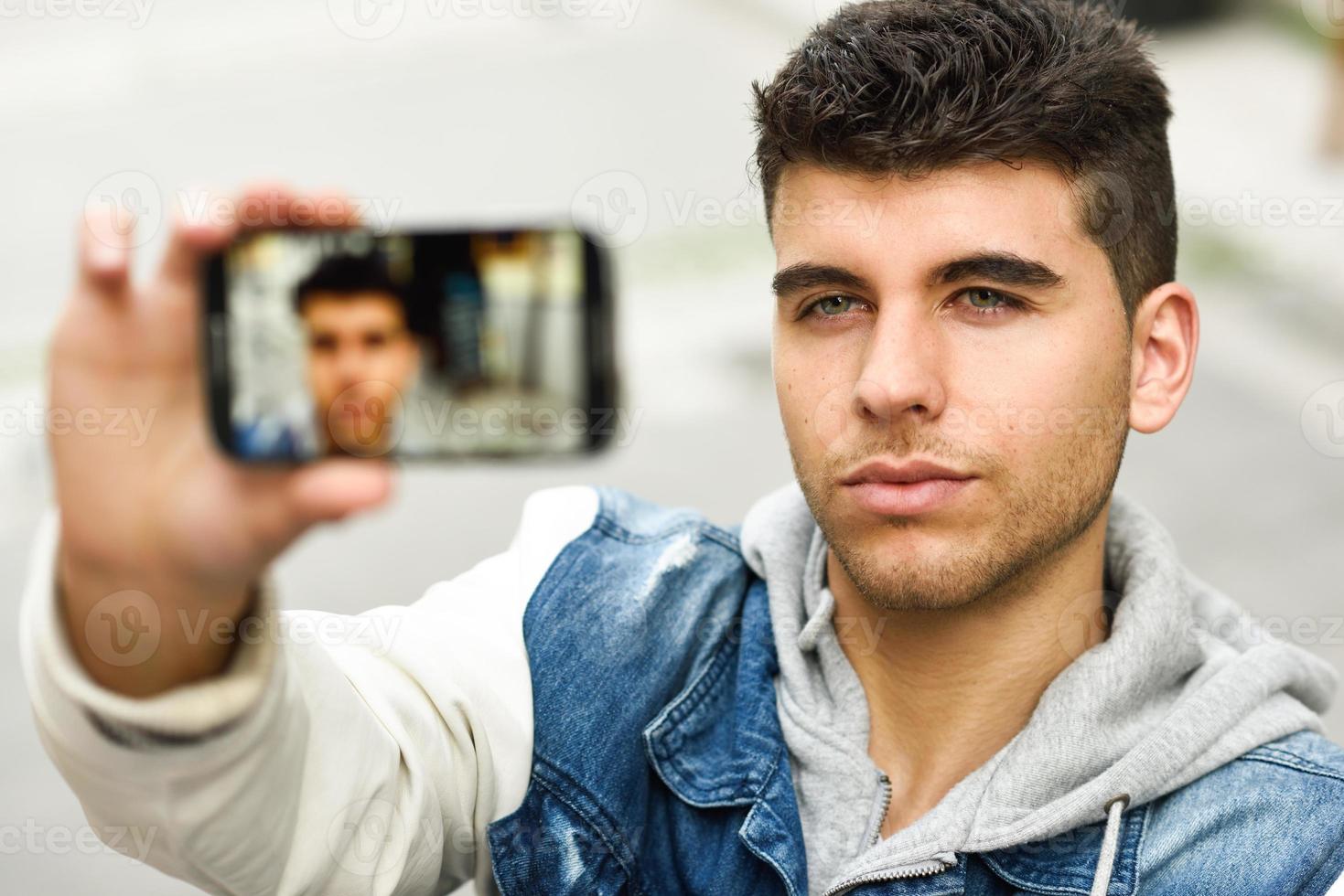 selfie di giovane uomo in fondo urbano con uno smartphone foto