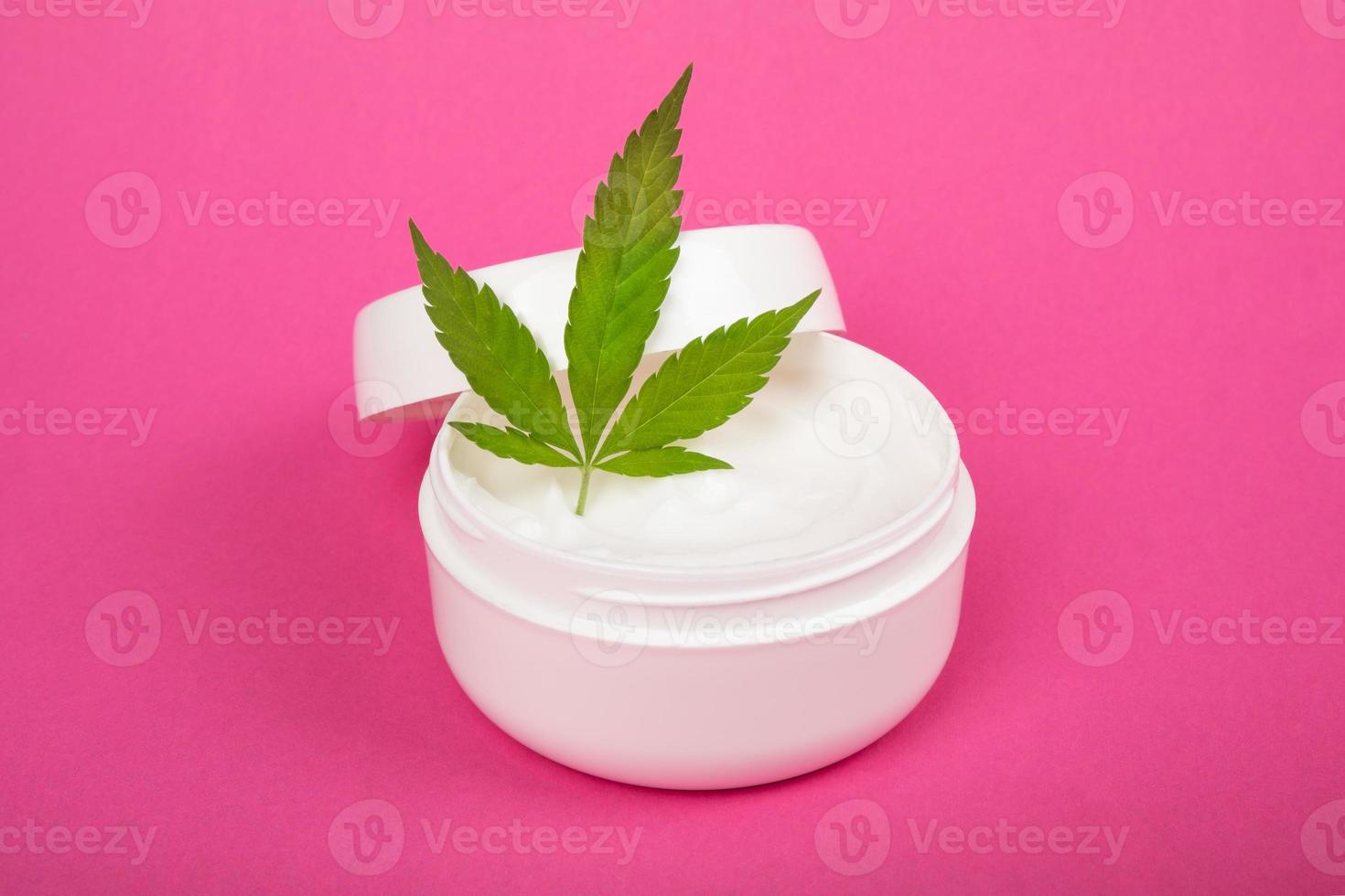 crema cosmetica per la cura della pelle con estratto di canapa su sfondo rosa foto