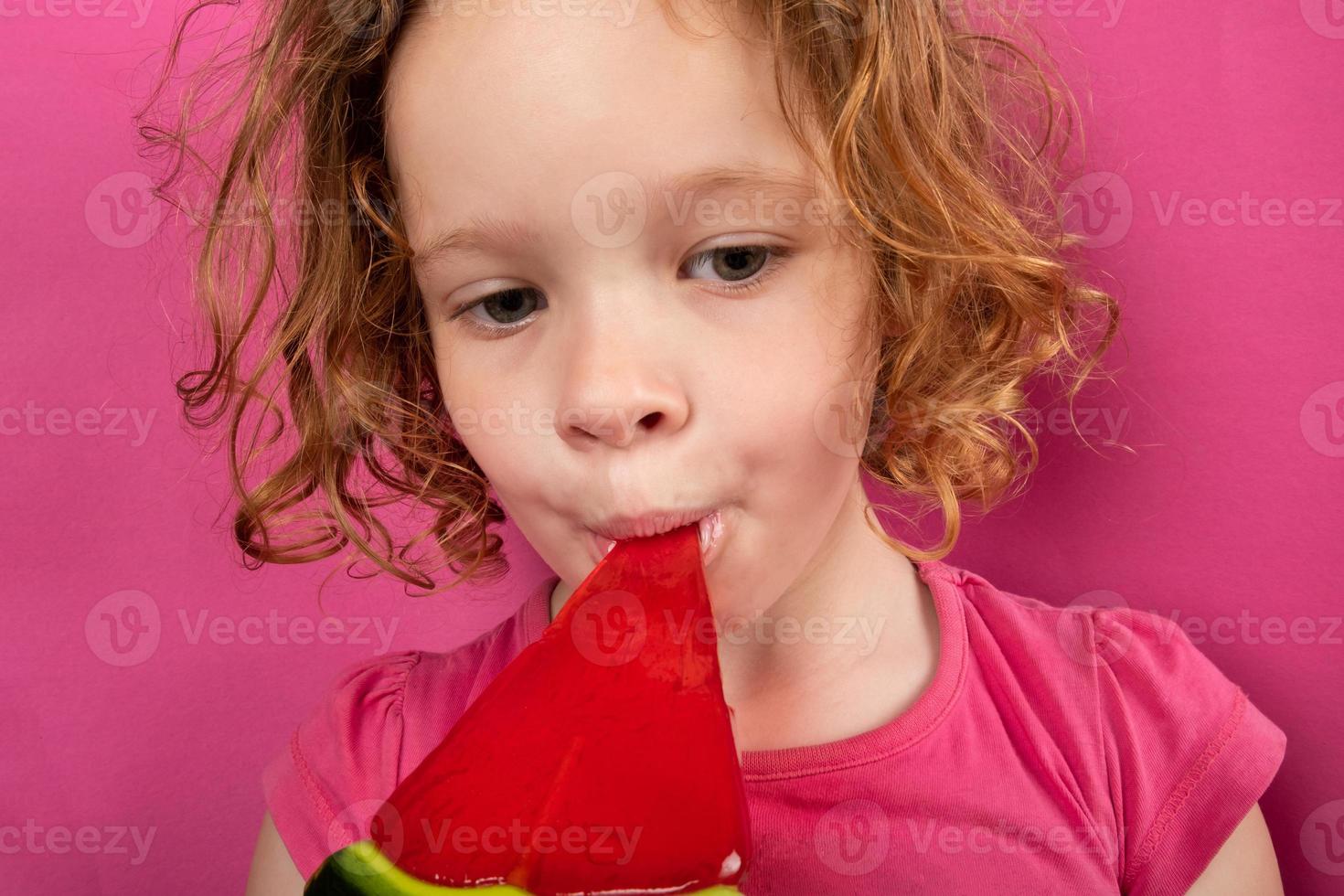 bambina che mangia caramelle all'anguria, i bambini adorano i dolci foto