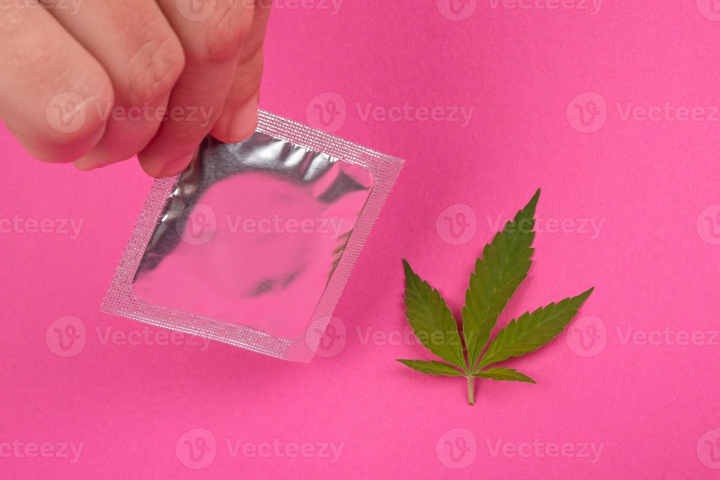 foglia di marijuana e preservativo, amore e droghe, contraccezione dopo l'assunzione della sostanza foto