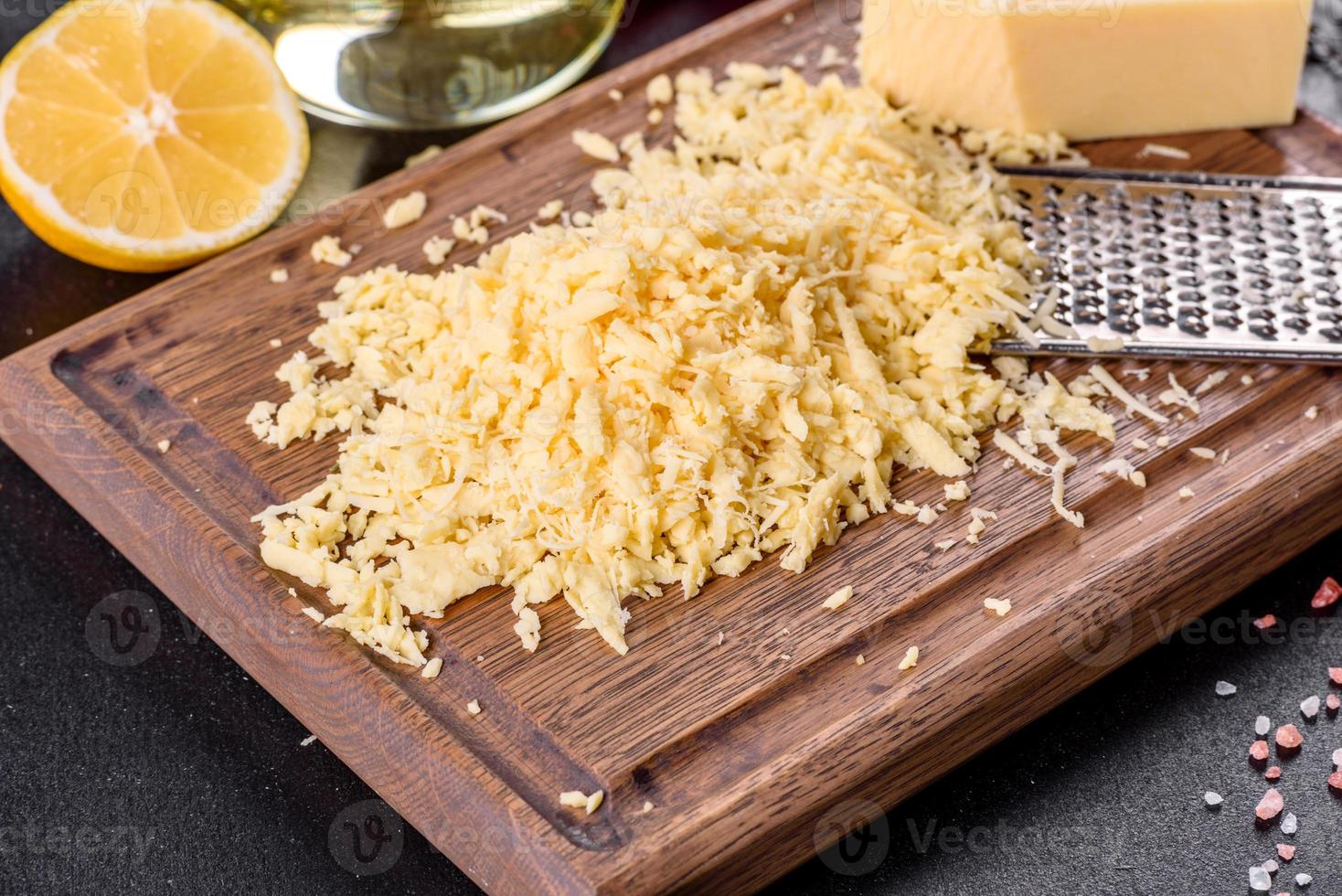 formaggio fresco a pasta dura grattugiato su una grattugia grande su un tagliere di legno foto