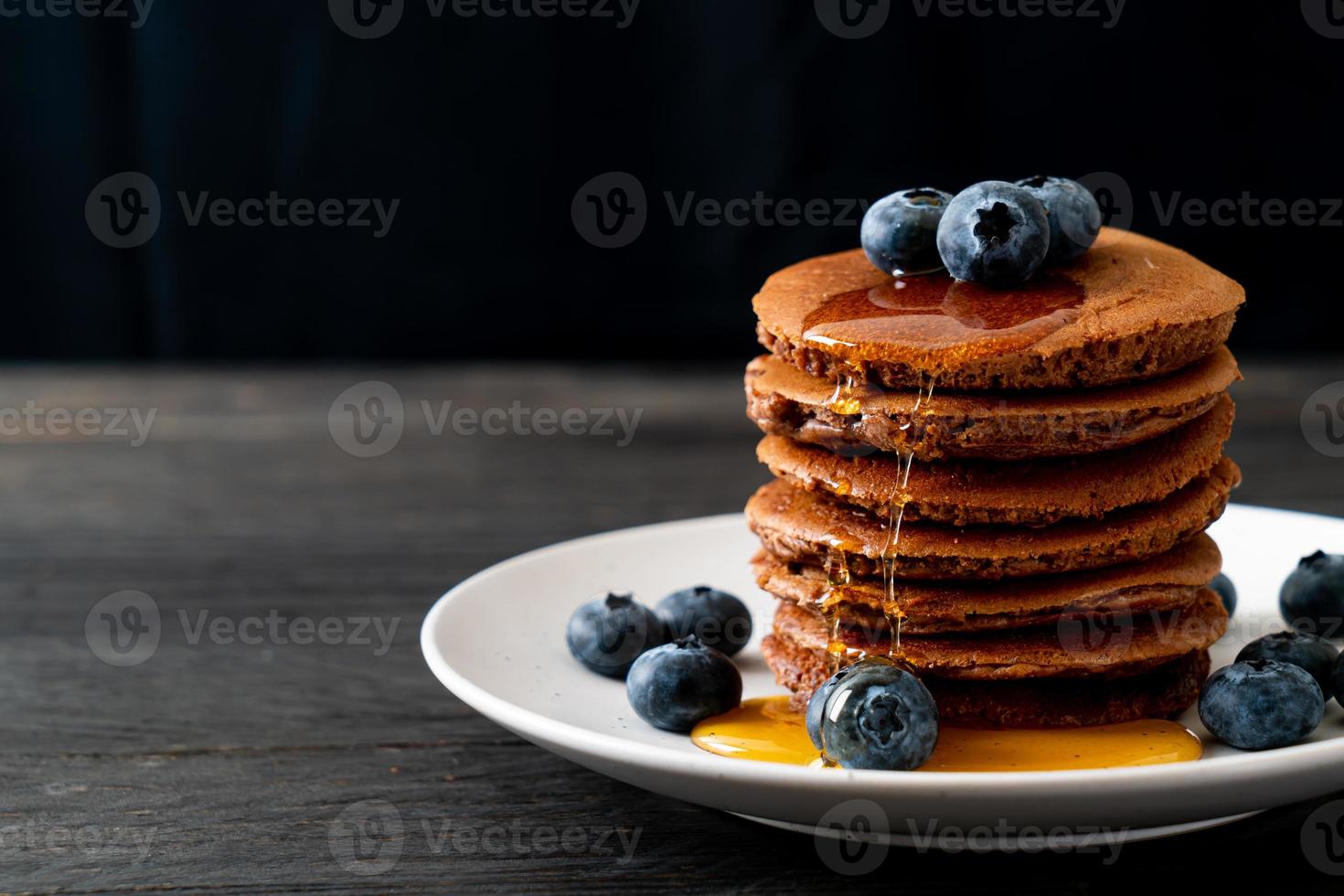 pila di pancake al cioccolato con mirtillo e miele su un piatto foto