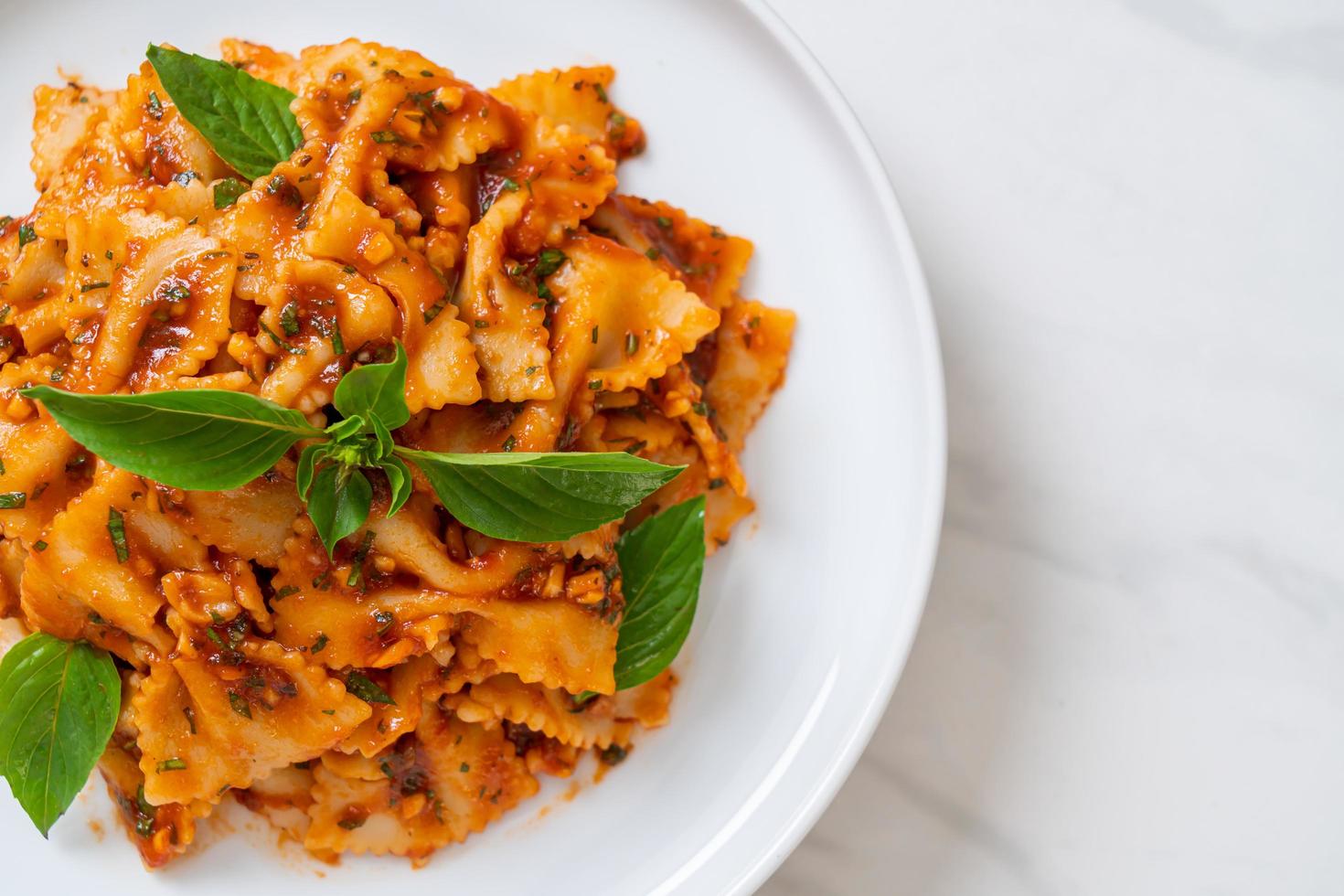 Farfalle con basilico e aglio in salsa di pomodoro - salsa italiana foto