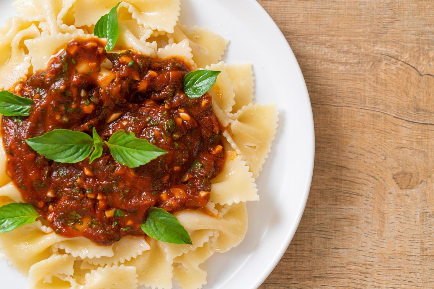 Farfalle con basilico e aglio in salsa di pomodoro - salsa italiana foto