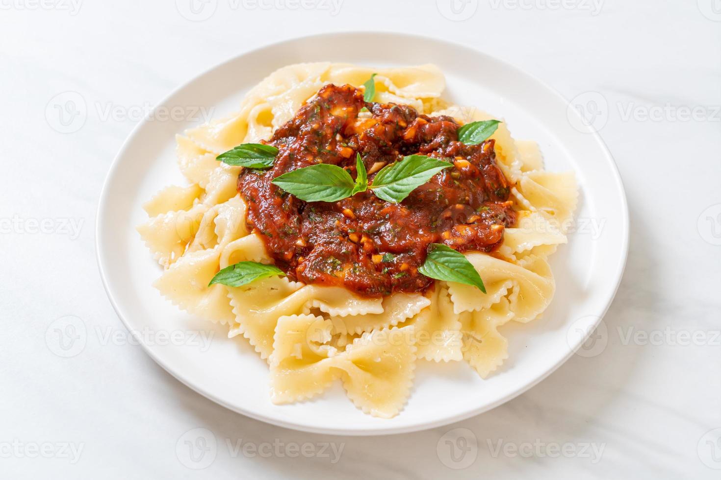 Farfalle con basilico e aglio in salsa di pomodoro - salsa italiana foto