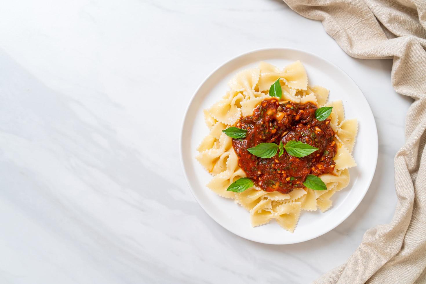 Farfalle con basilico e aglio in salsa di pomodoro - salsa italiana foto