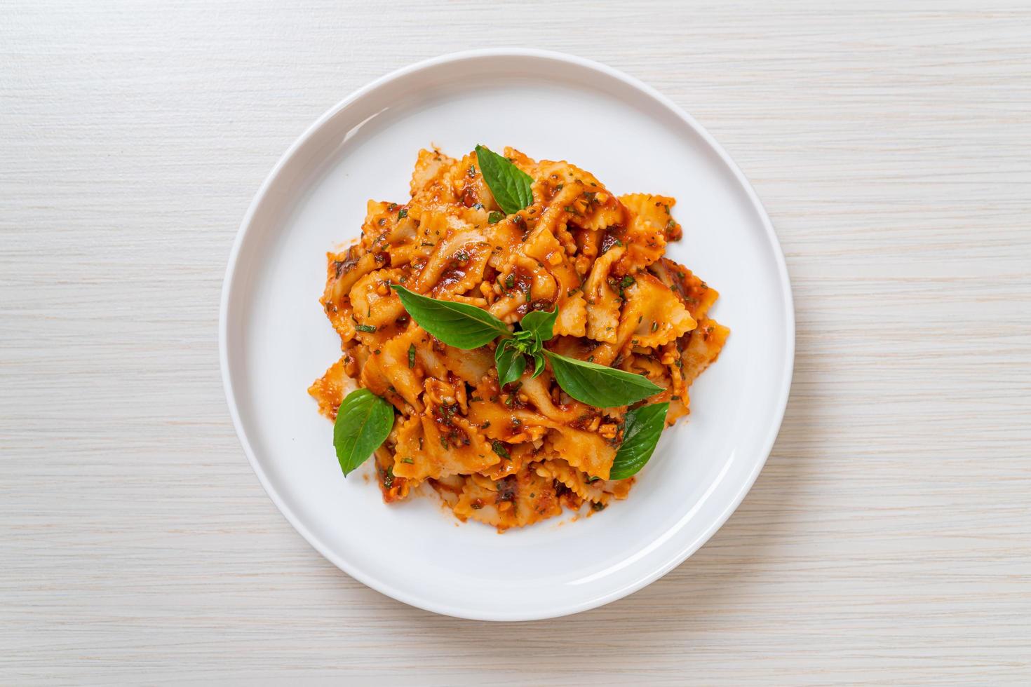 Farfalle con basilico e aglio in salsa di pomodoro - salsa italiana foto