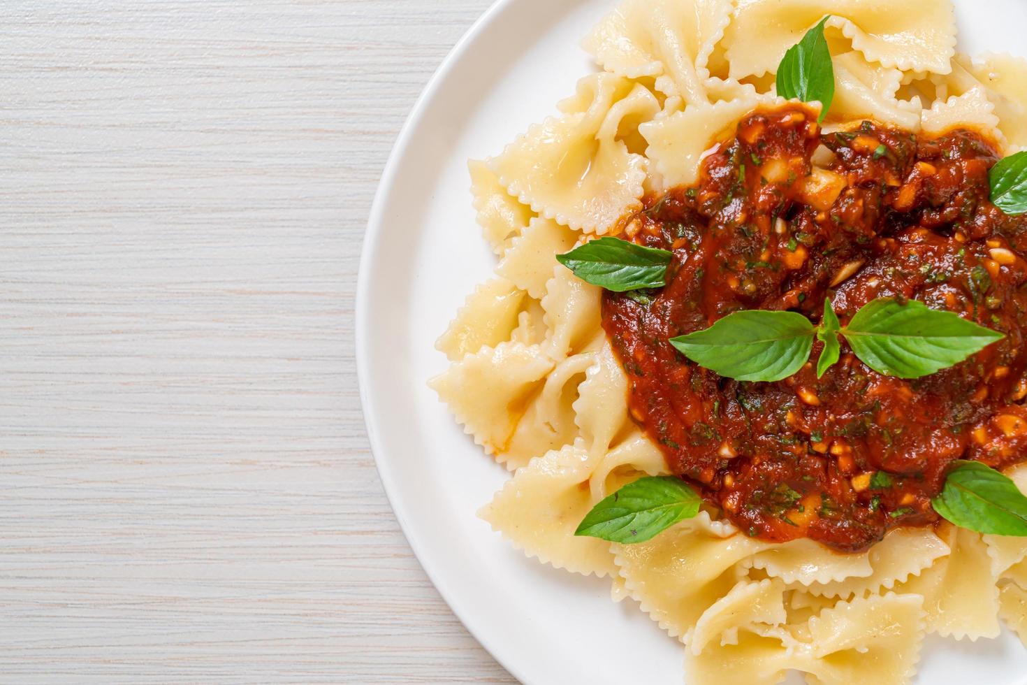 Farfalle con basilico e aglio in salsa di pomodoro - salsa italiana foto