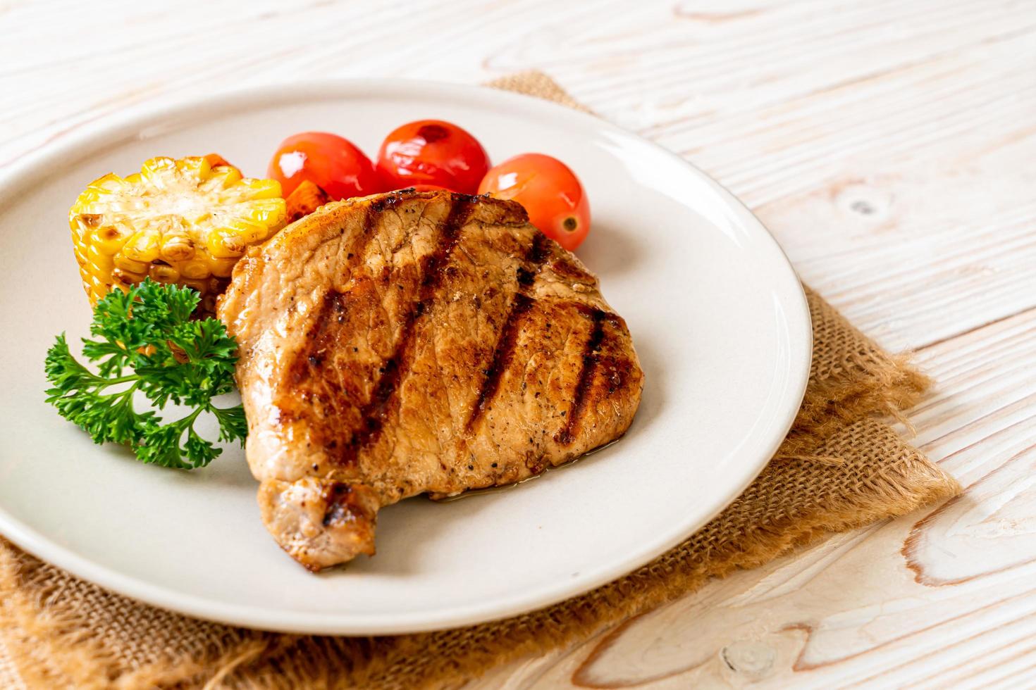 Filetto di maiale alla griglia e alla brace con mais, carota e pomodori foto