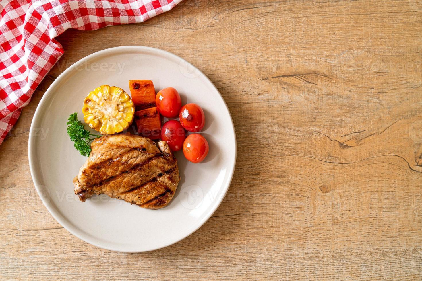 Filetto di maiale alla griglia e alla brace con mais, carota e pomodori foto