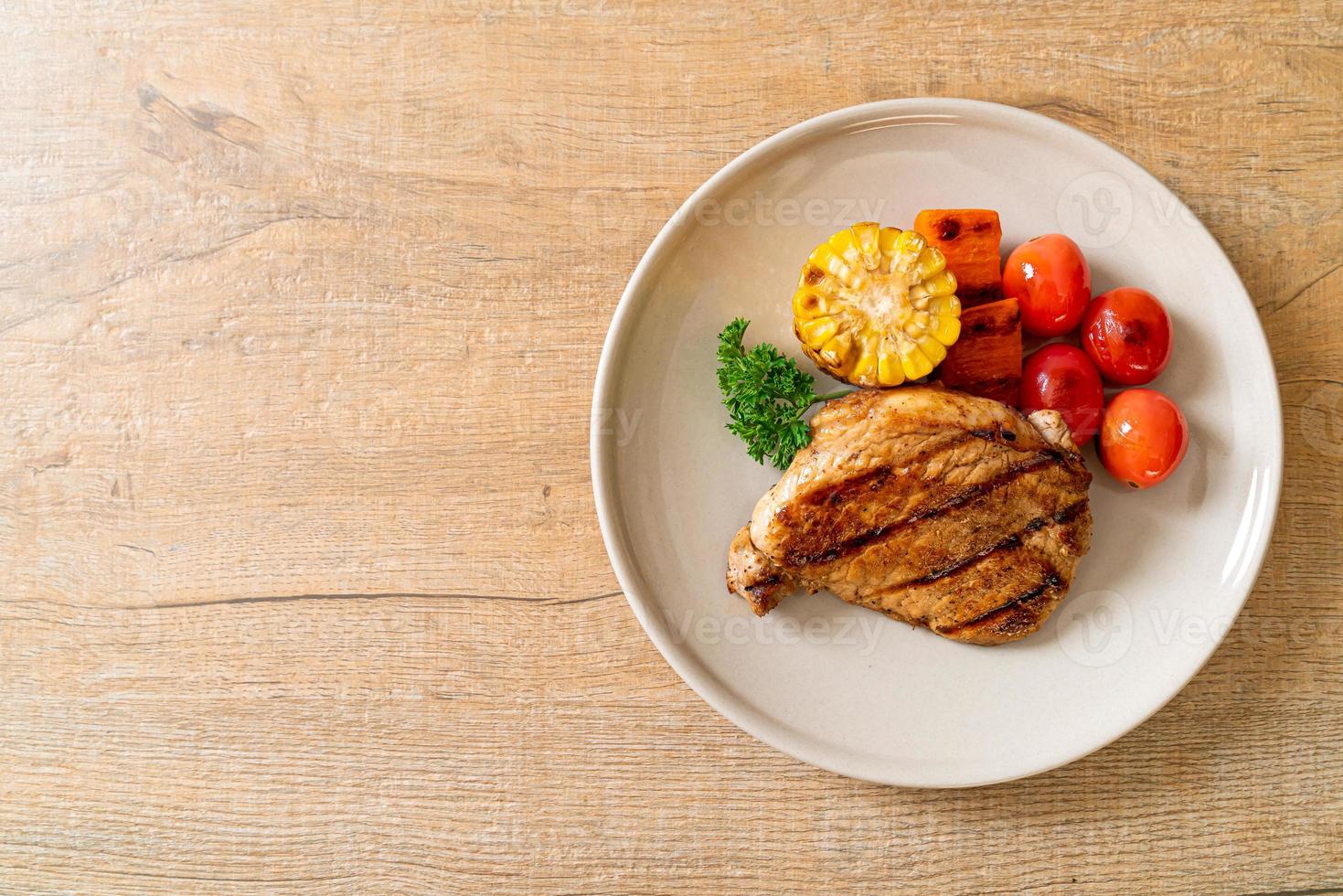 Filetto di maiale alla griglia e alla brace con mais, carota e pomodori foto