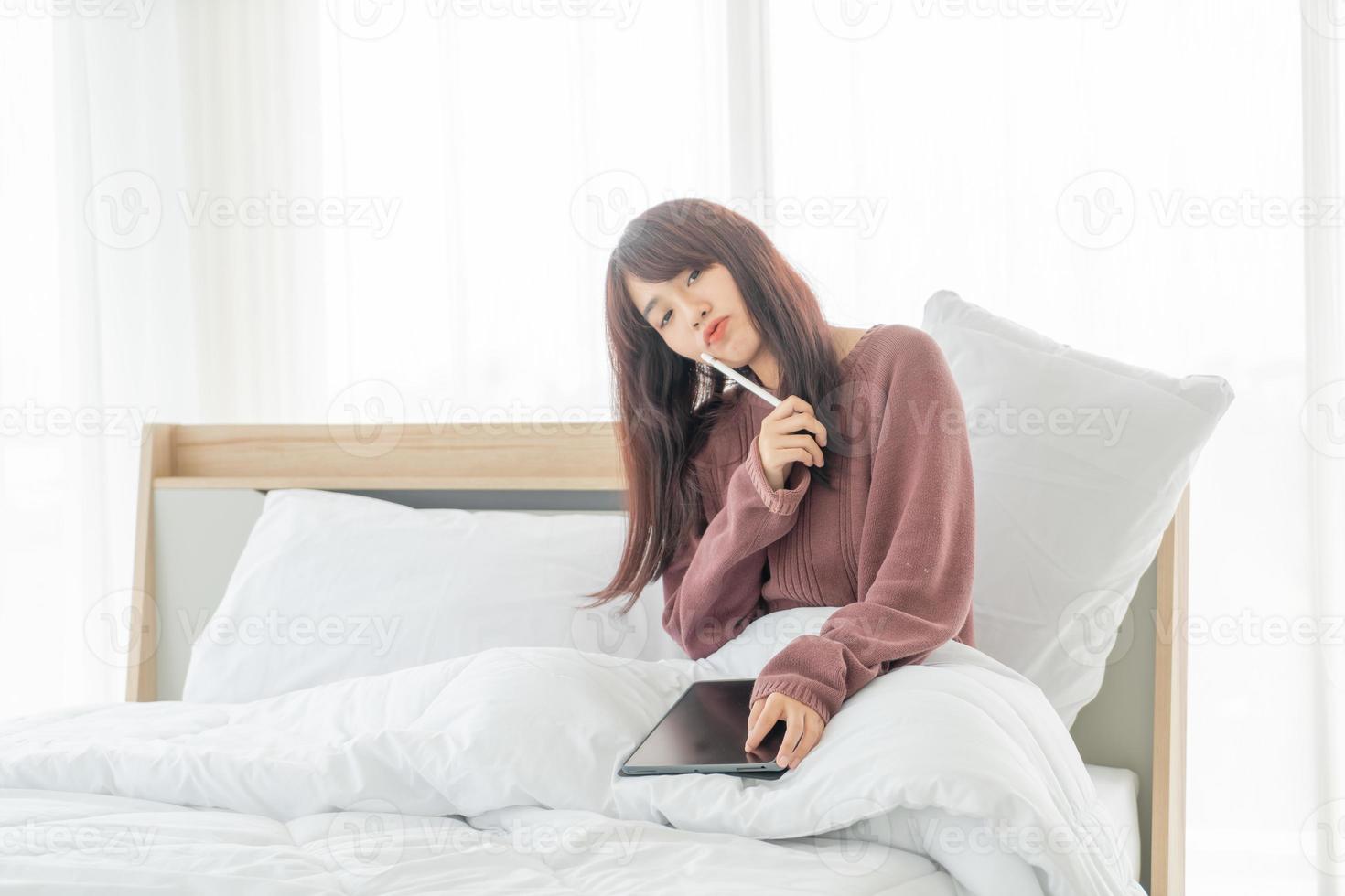 bella donna asiatica che lavora con tablet sul letto? foto