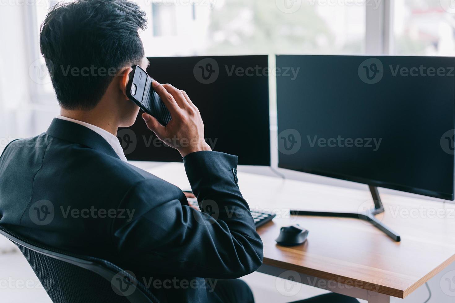 uomo d'affari asiatico concentrato sul lavoro mentre è al telefono foto