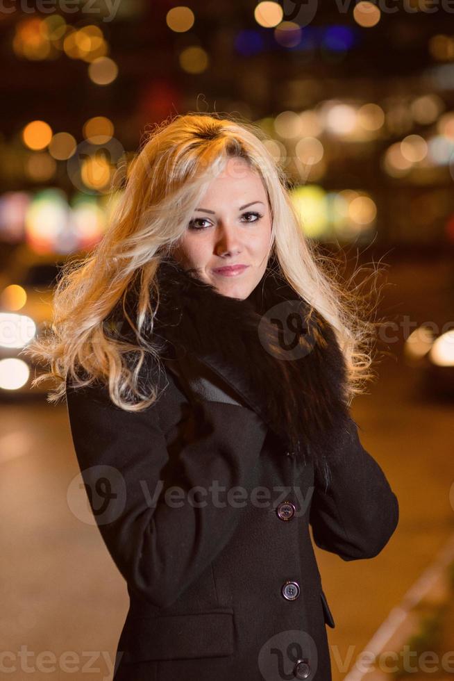 bella donna bionda nelle luci dell'auto nella città di notte. foto