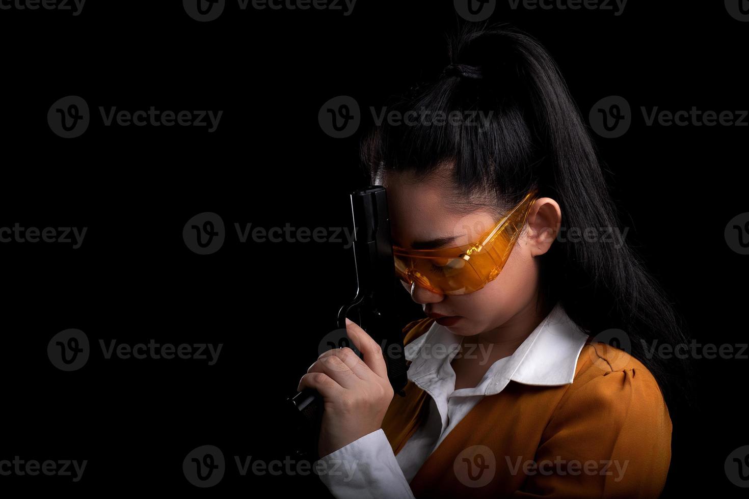 asea donna che indossa un abito giallo una mano che tiene una pistola pistola a sfondo nero foto