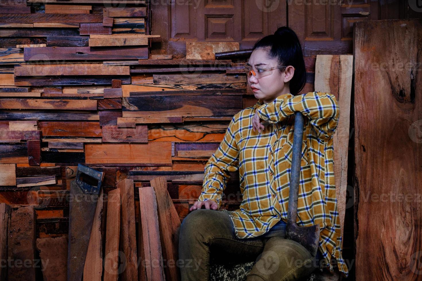 donne del carpentiere che si siedono con la presa dell'ascia al vecchio fondo della parete di legno wood foto