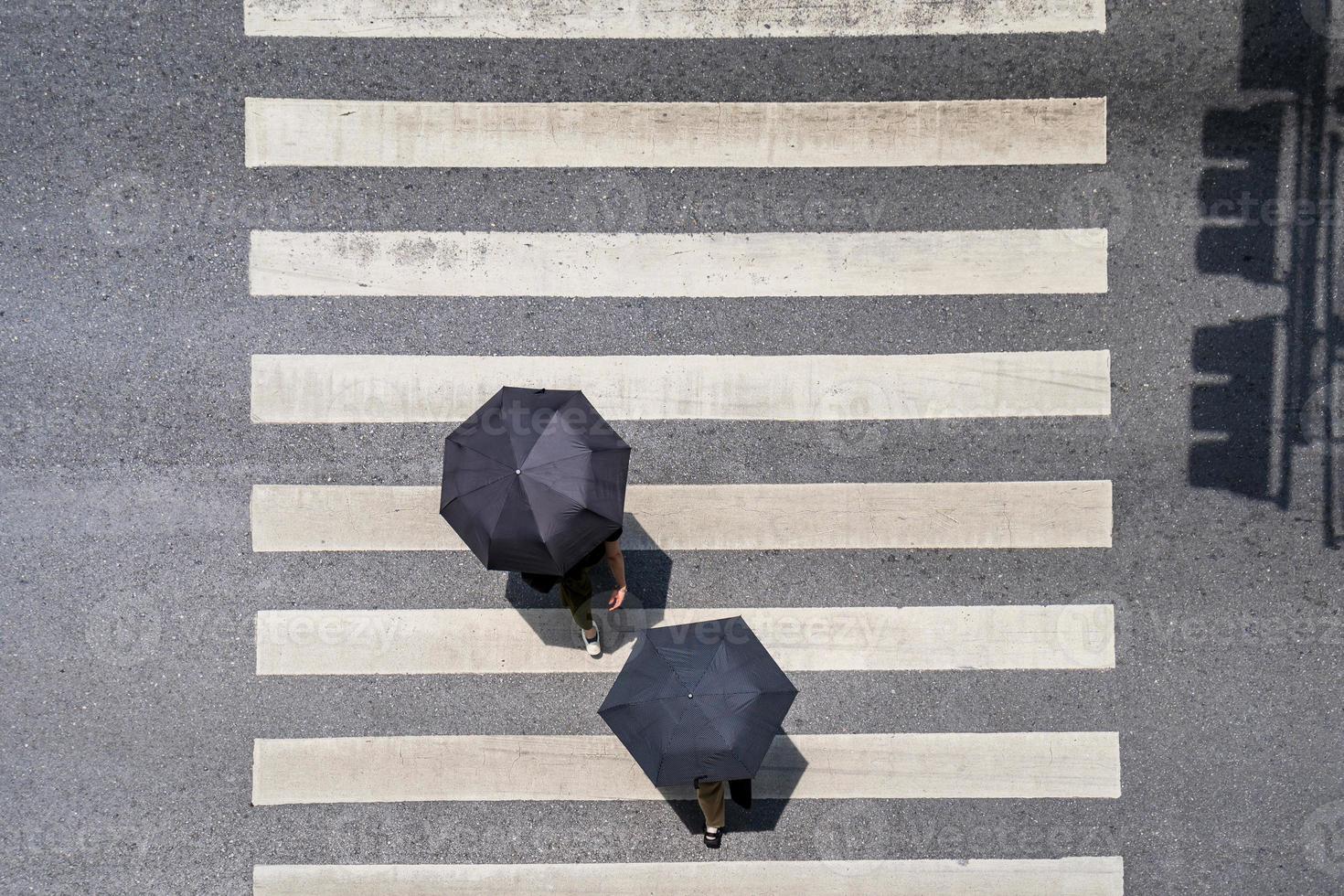 foto aerea vista dall'alto di persone sotto l'ombrellone a piedi sulla strada della città sopra l'attraversamento pedonale strada di traffico