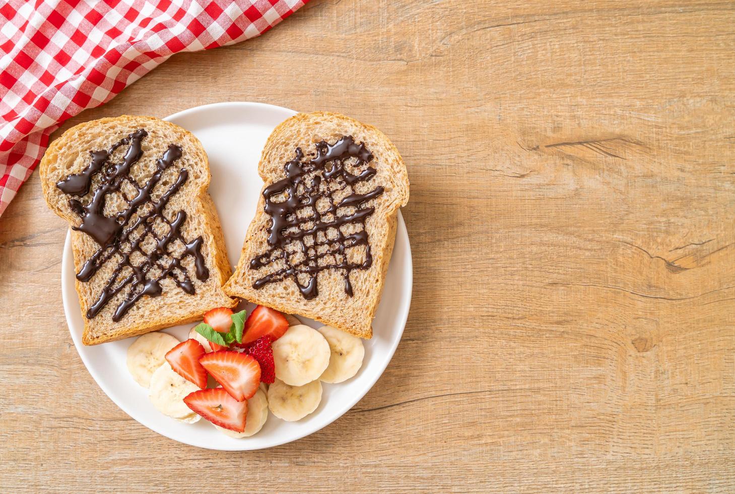 pane integrale tostato con banana fresca, fragola e cioccolato per colazione foto