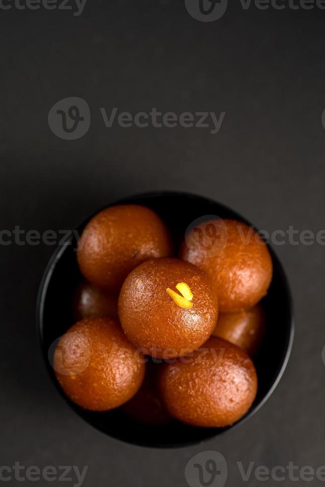 gulab jamun in una ciotola su sfondo nero. dessert indiano o piatto dolce. foto