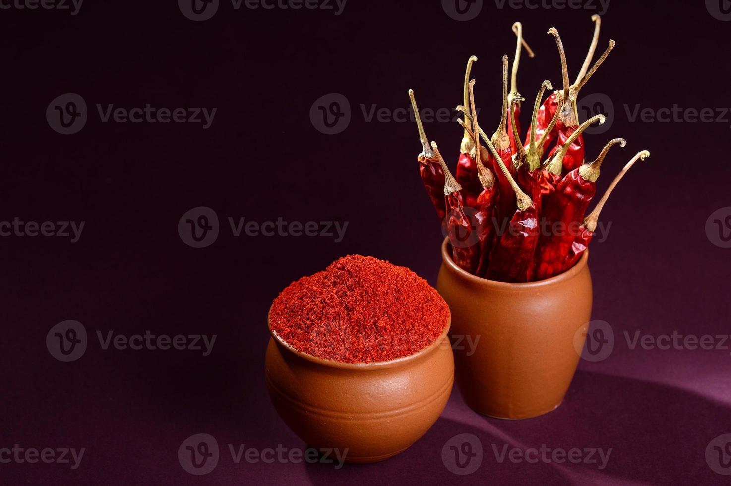 polvere fredda con peperoncino rosso in vasi di argilla, peperoncini secchi su sfondo scuro foto