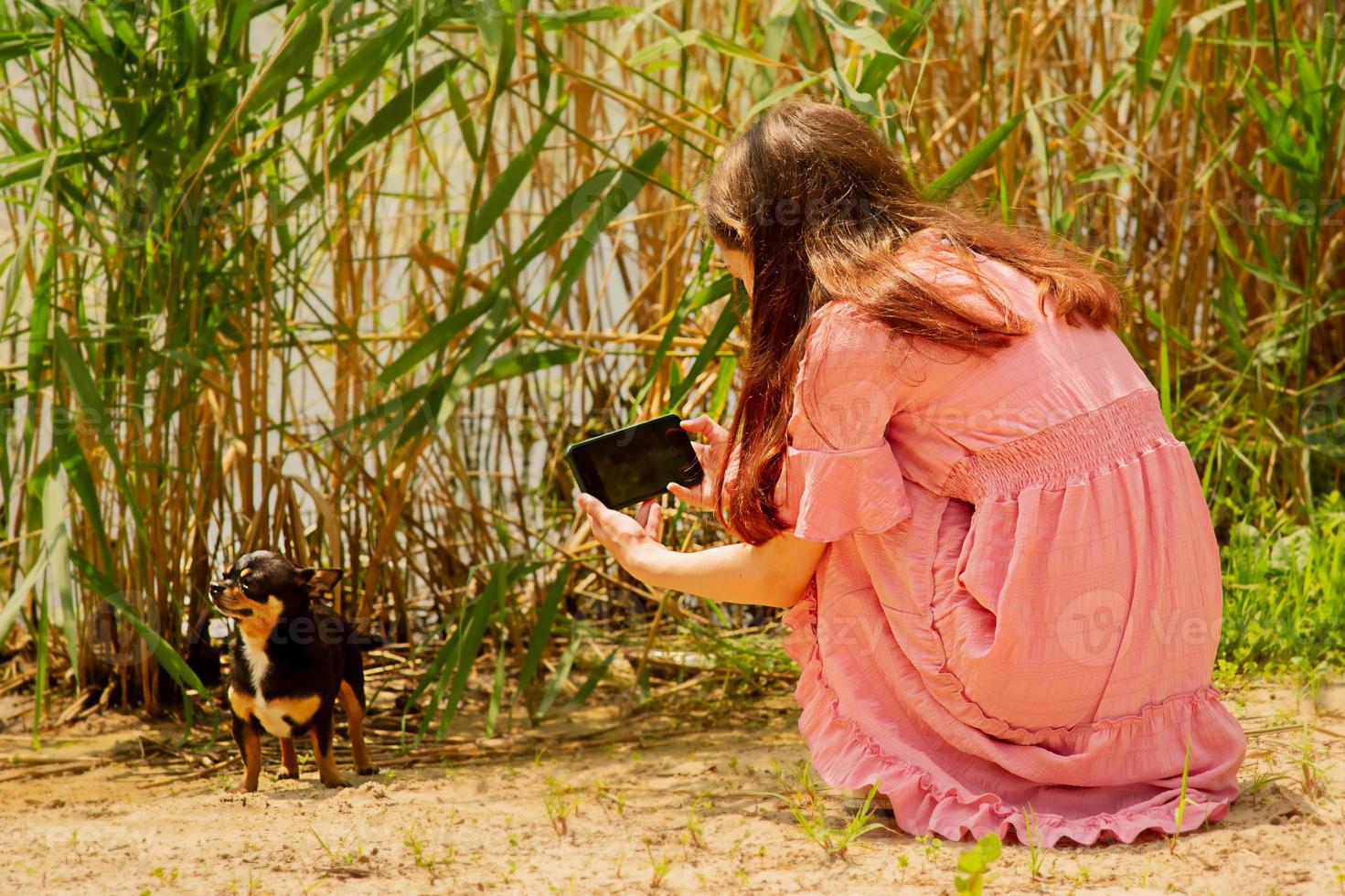 ragazza adolescente che scatta foto al suo cane con la fotocamera del cellulare