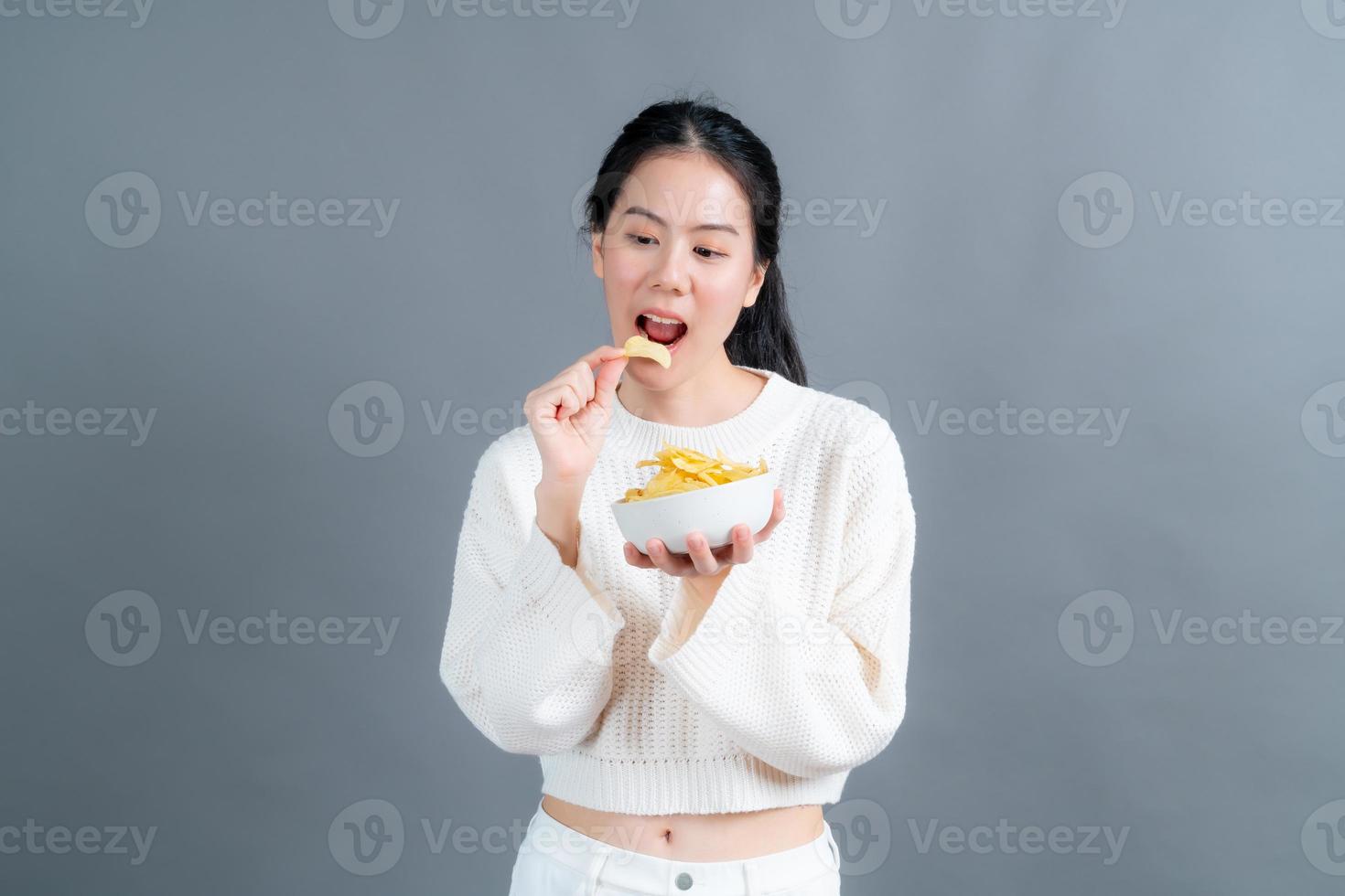 la giovane donna asiatica mangia le patatine fritte foto