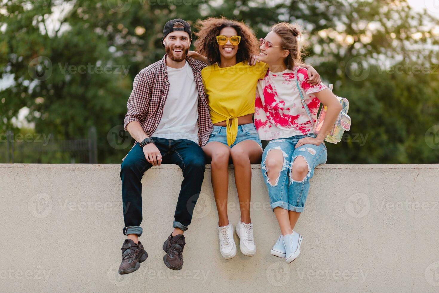 contento giovane azienda di sorridente amici seduta nel parco foto