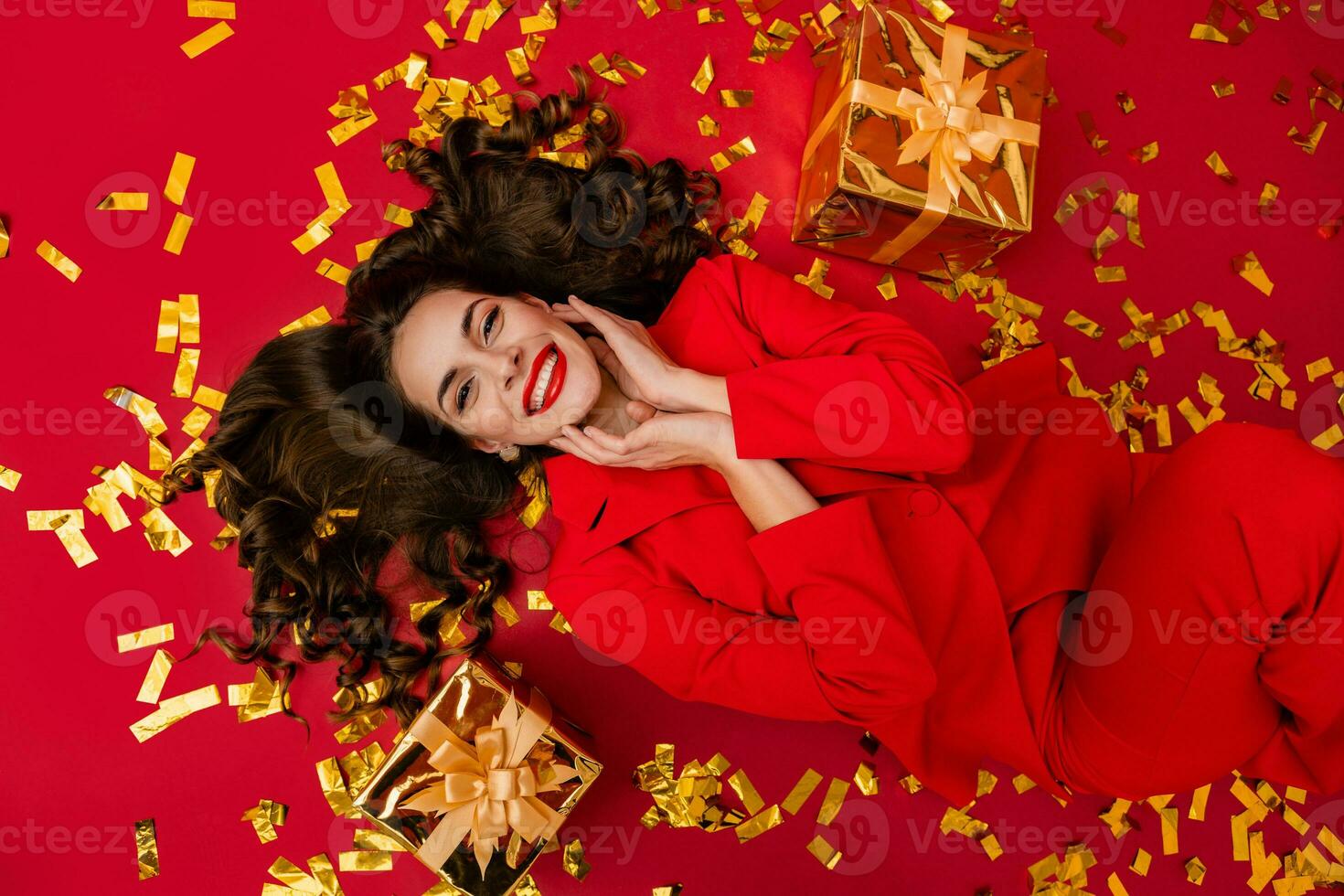 attraente donna festeggiare Natale su rosso sfondo nel coriandoli foto