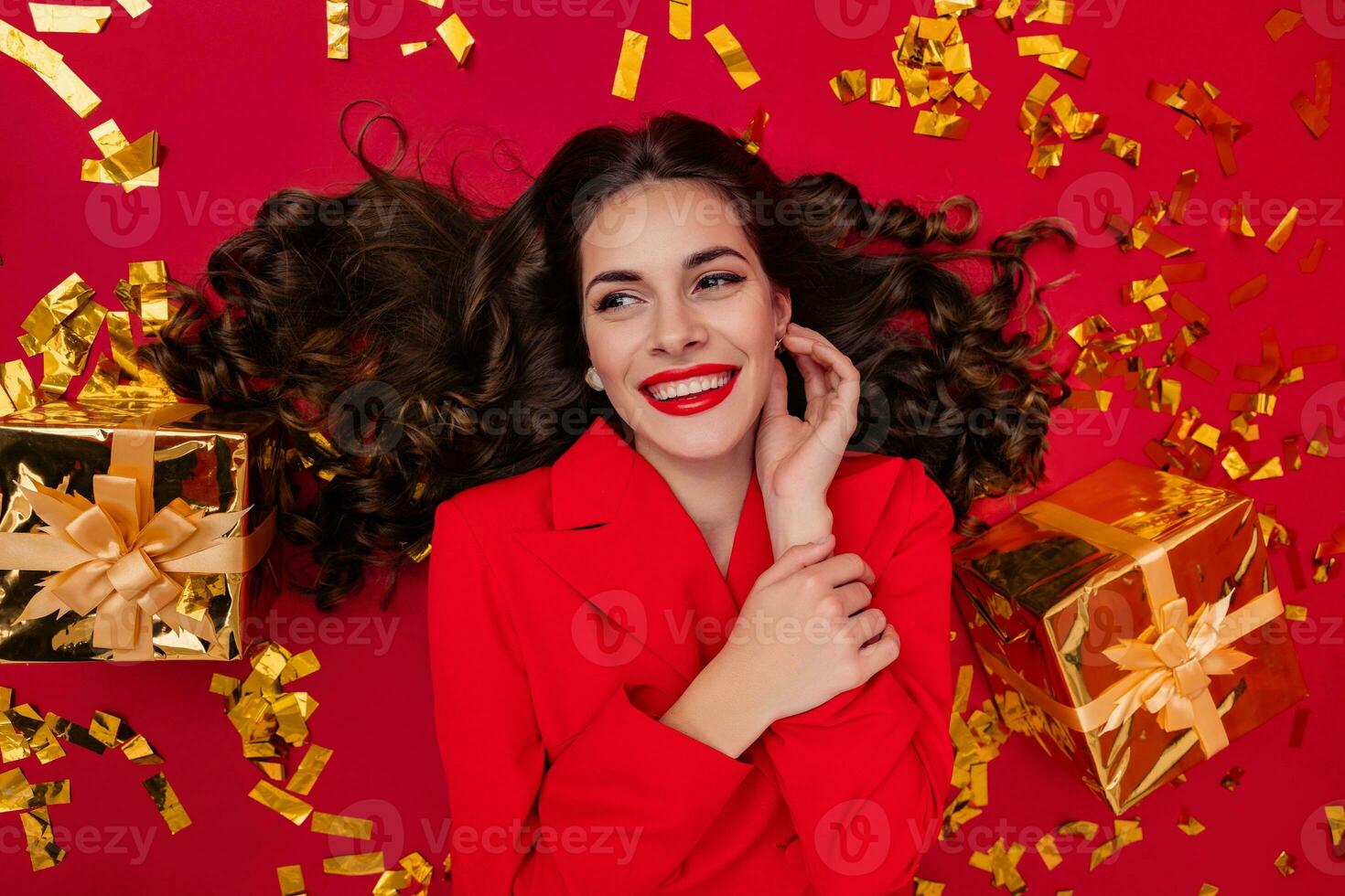 attraente donna festeggiare Natale su rosso sfondo nel coriandoli foto