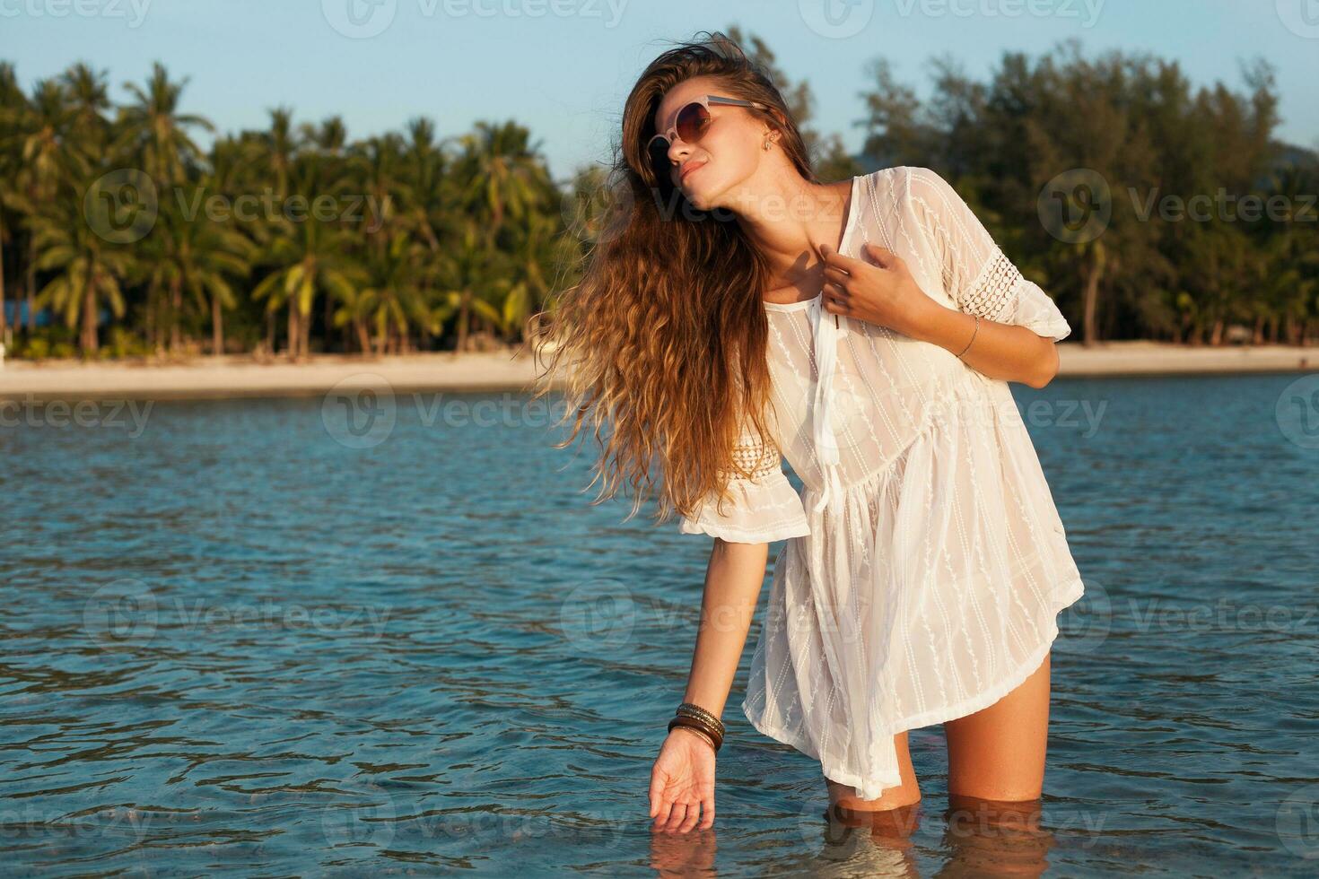 sottile bellissimo donna nel bianca cotone vestito a piedi su tropicale spiaggia foto