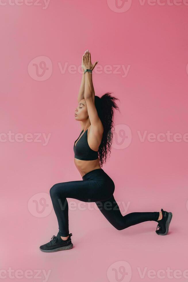 attraente nero africano americano donna nel nero leggins fitness attrezzatura su rosa sfondo foto