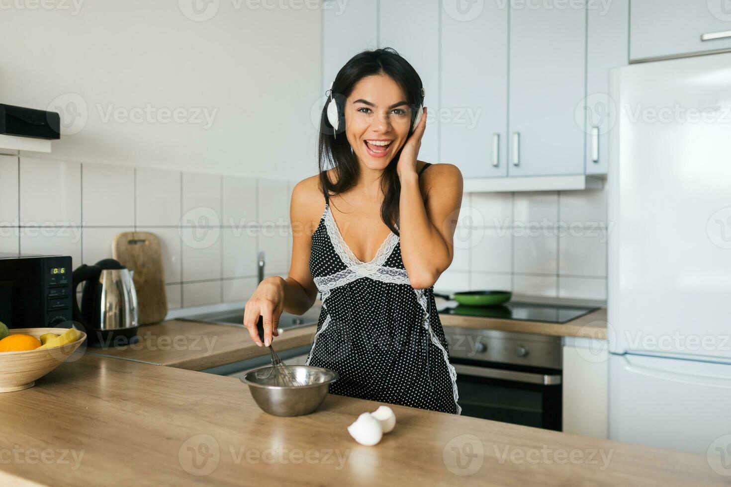 attraente sorridente donna nel pigiama avendo prima colazione nel cucina foto