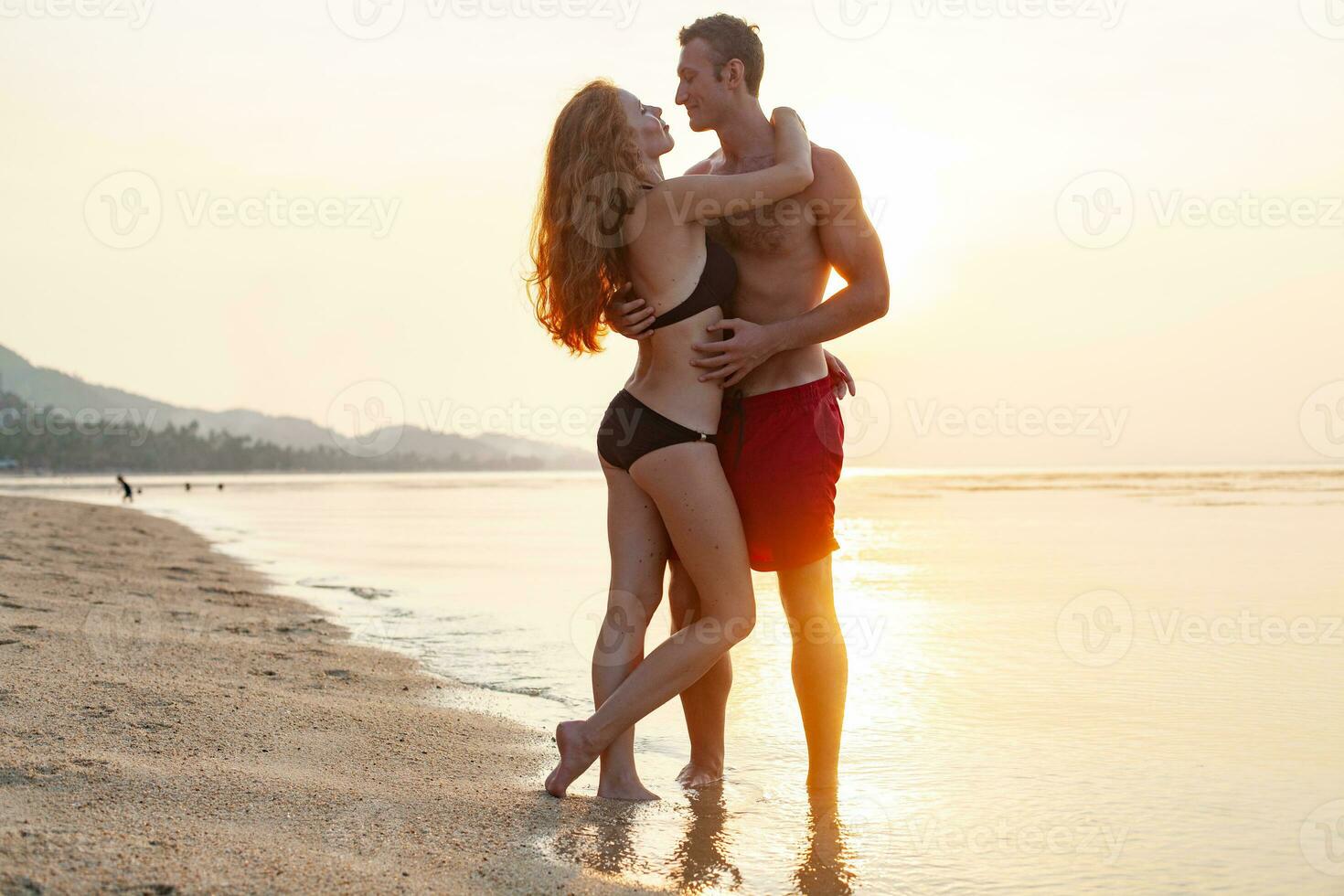 giovane sexy romantico coppia nel amore contento su estate spiaggia insieme avendo divertimento indossare nuotare tute foto