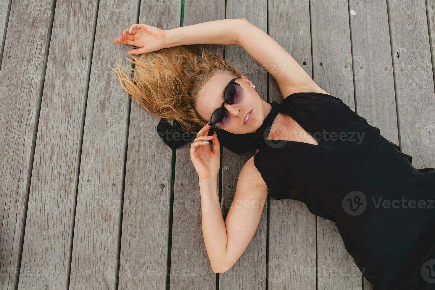 lusso sexy attraente donna vestito nel romantico nero vestito dire bugie su pavimento foto