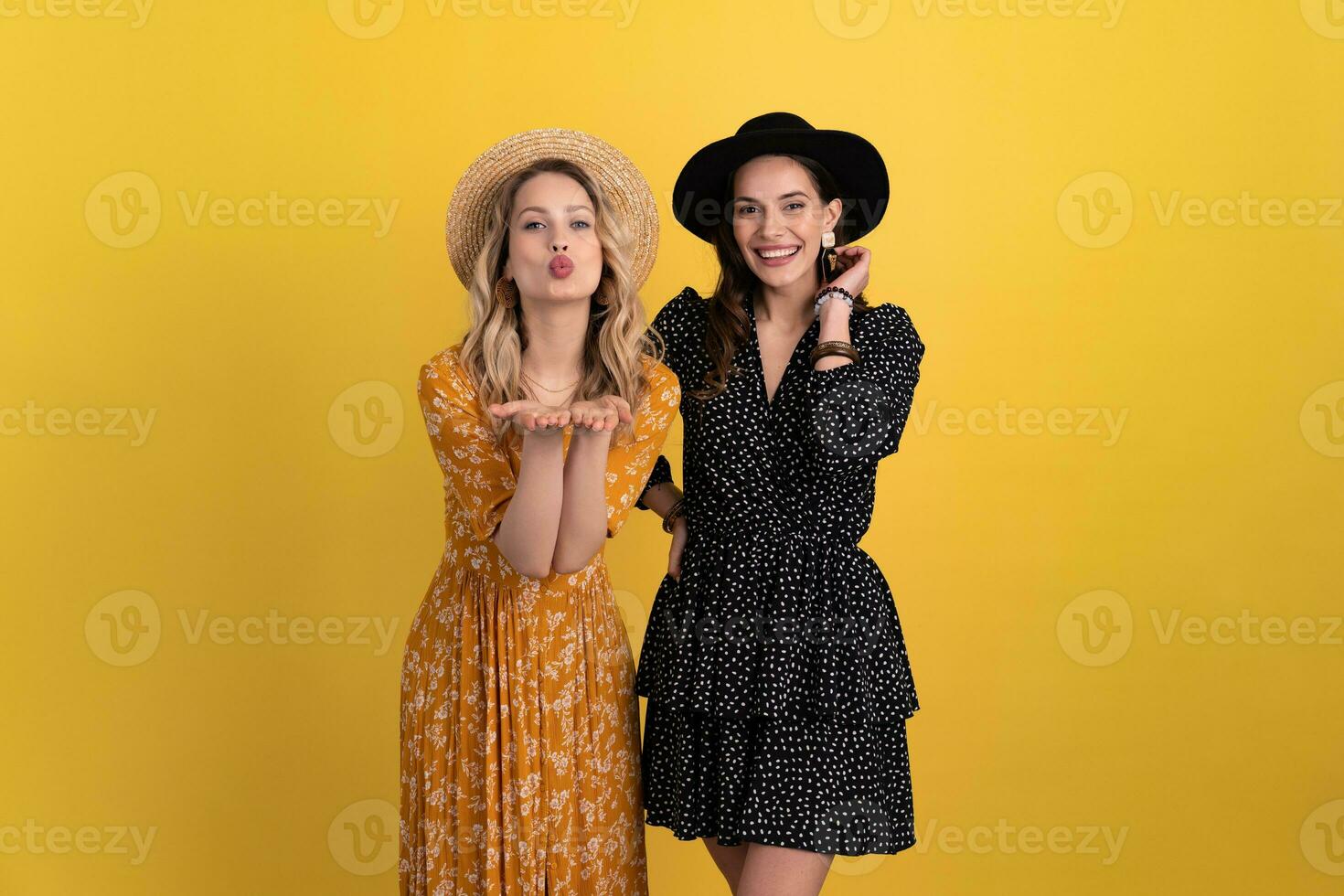 bellissimo donne amici insieme isolato su giallo sfondo nel nero e giallo vestito e cappello foto