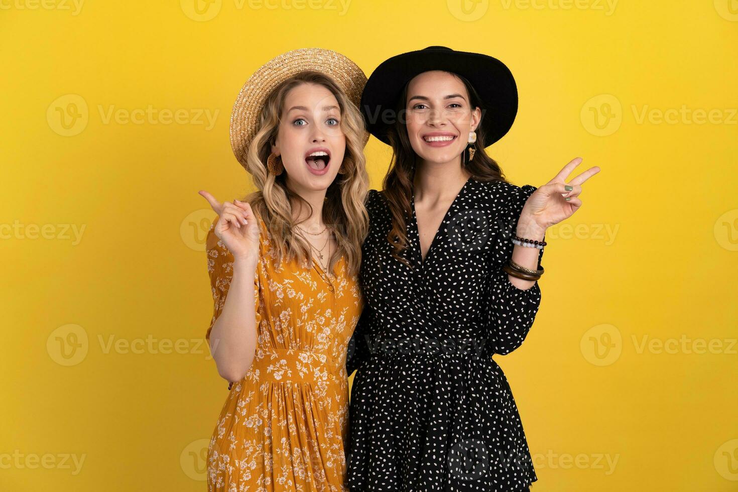 bellissimo donne amici insieme isolato su giallo sfondo nel nero e giallo vestito e cappello foto