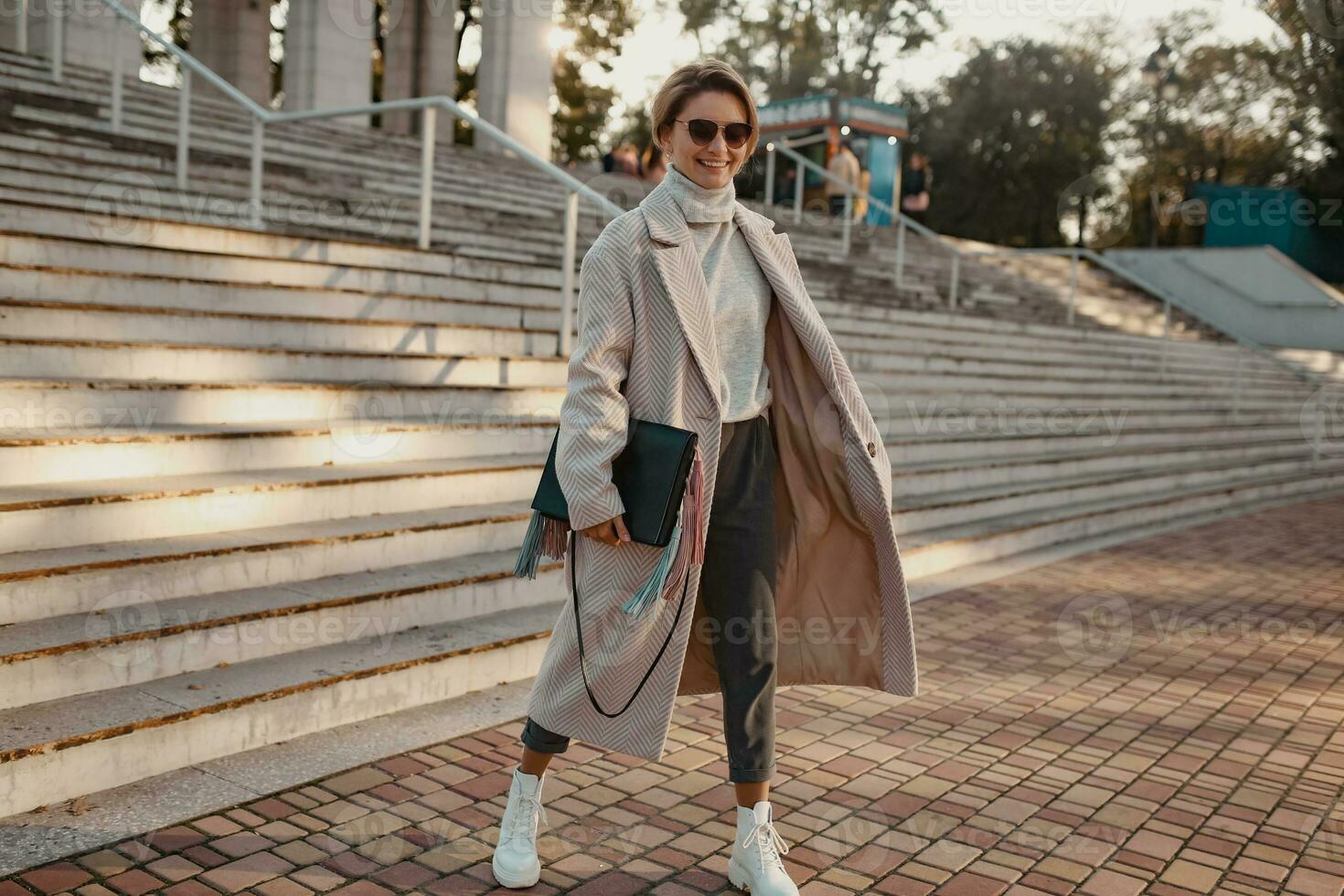 elegante alla moda donna a piedi nel strada nel elegante stile cappotto foto