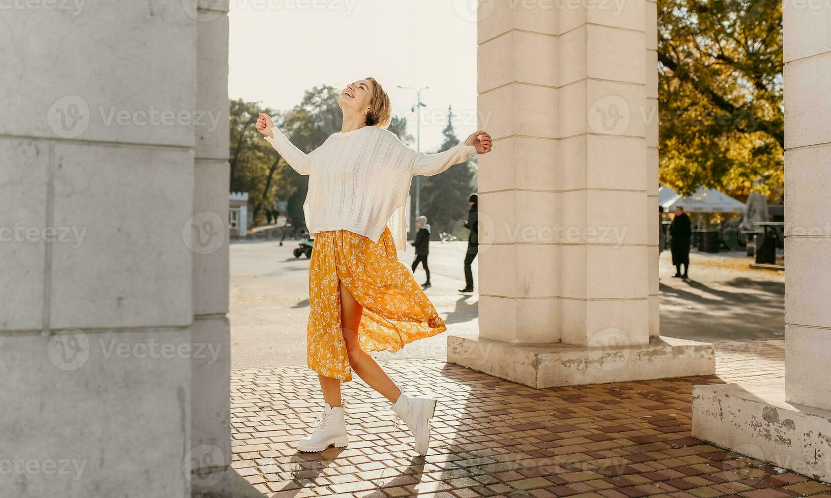 giovane bella contento sorridente donna nel giallo stampato vestito e a maglia bianca maglione foto