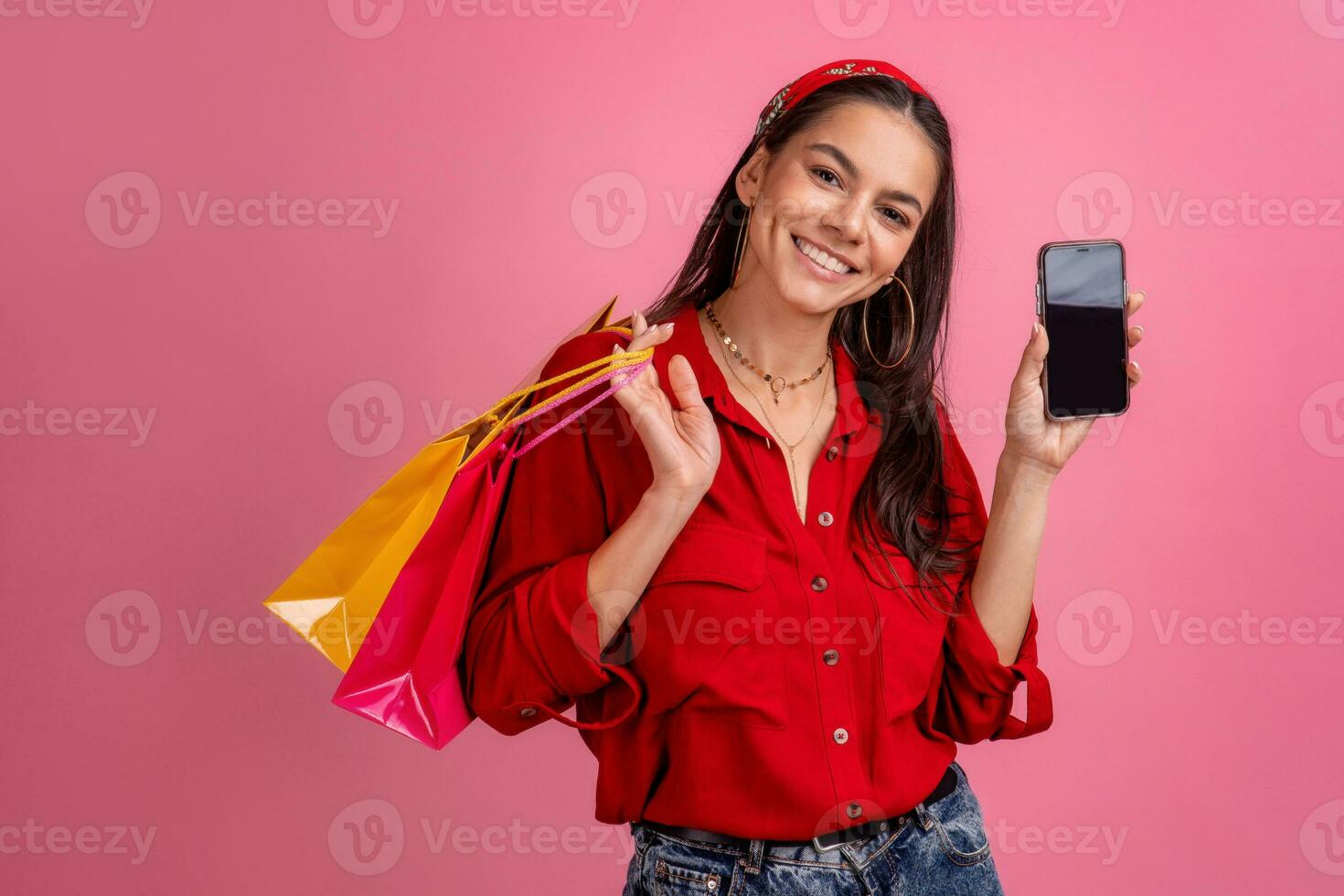 ispanico bellissimo donna nel rosso camicia sorridente Tenere Tenere shopping borse e smartphone foto