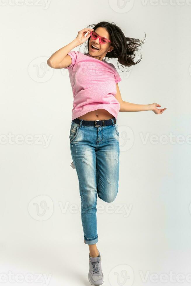 attraente donna nel rosa maglietta e occhiali da sole salto foto