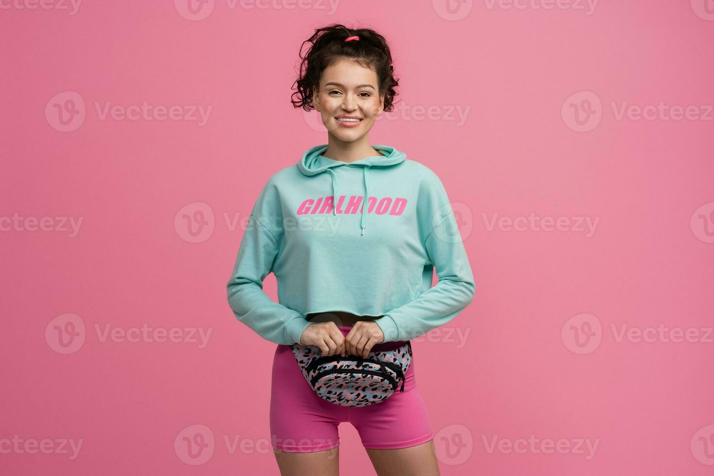 sorridente contento bellissimo donna nel elegante gli sport attrezzatura in posa su rosa sfondo isolato nel studio foto