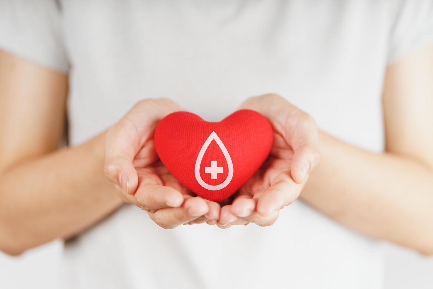 le mani della donna che tengono il cuore rosso con il segno del donatore di sangue. concetto di assistenza sanitaria, medicina e donazione di sangue foto