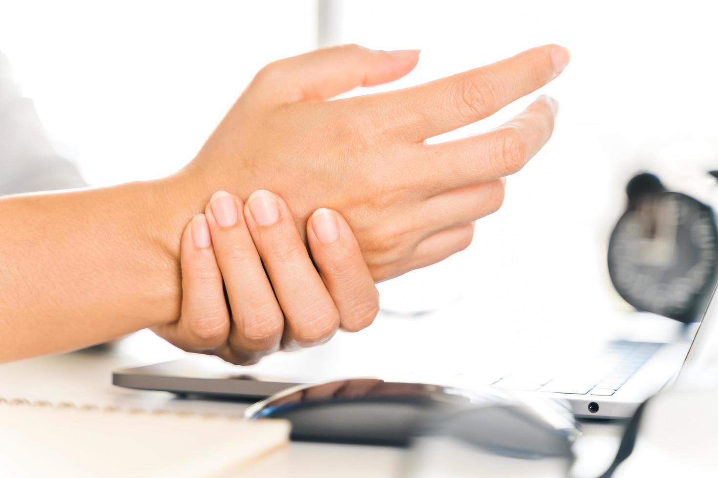 donna del primo piano che tiene il suo dolore alla mano dall'uso del computer da molto tempo. concetto di sindrome dell'ufficio. foto