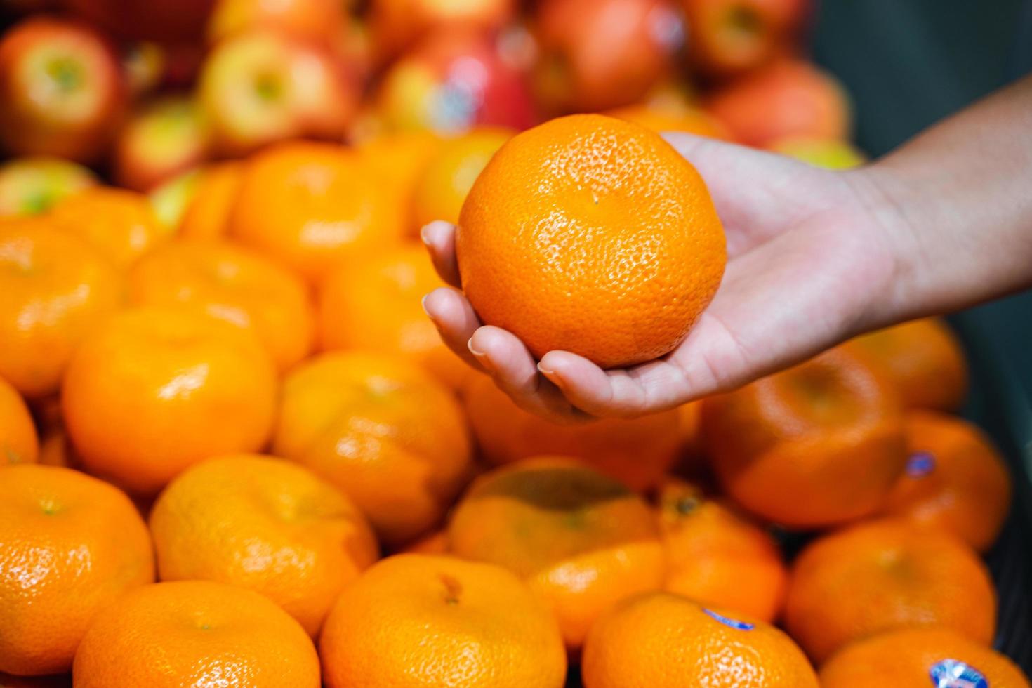 mano della donna che sceglie un'arancia al supermercato foto