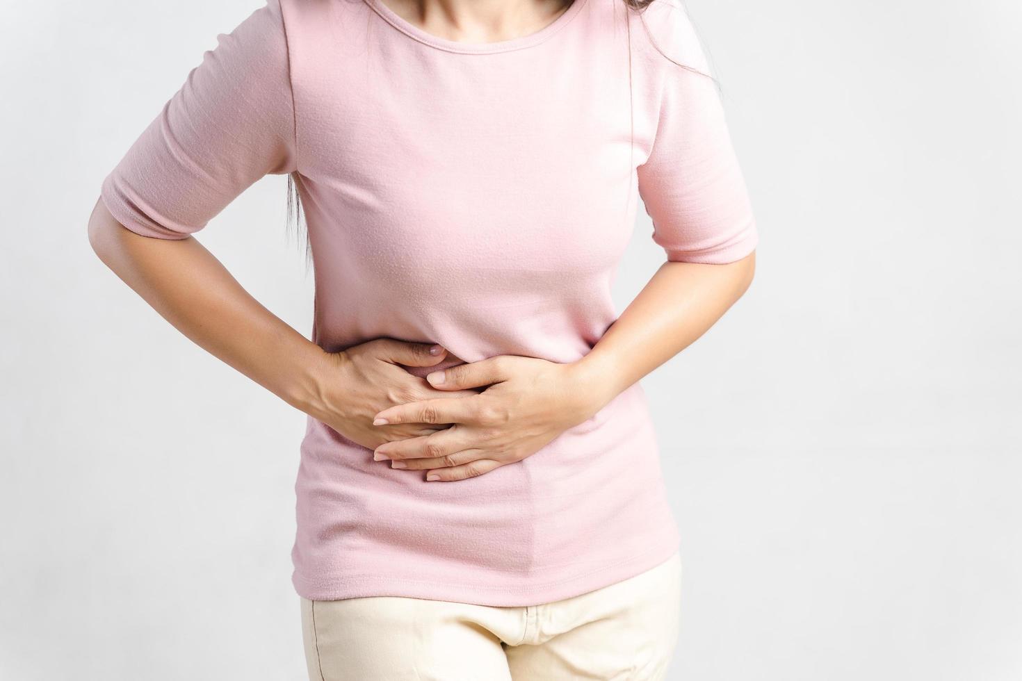 giovane bella donna che ha mal di stomaco doloroso su bianco background.chronic gastrite. concetto di gonfiore addominale. foto