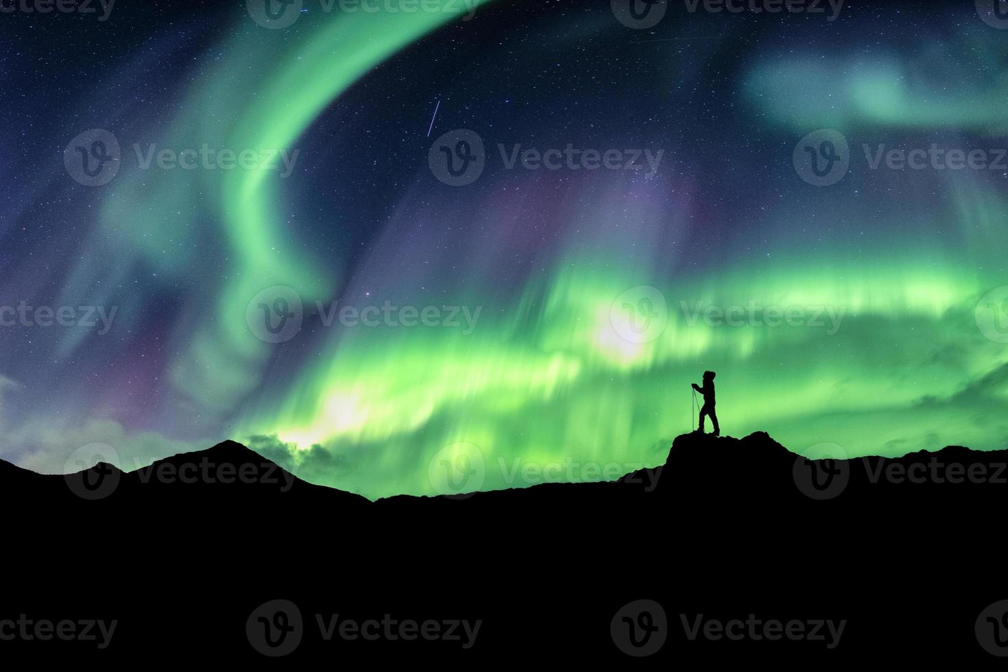 uomo che fa un'escursione in montagna con l'esplosione dell'aurora boreale foto