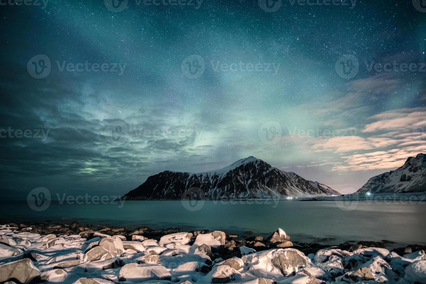 aurora boreale con stelle sulla catena montuosa con costa innevata sulla spiaggia di skagsanden foto