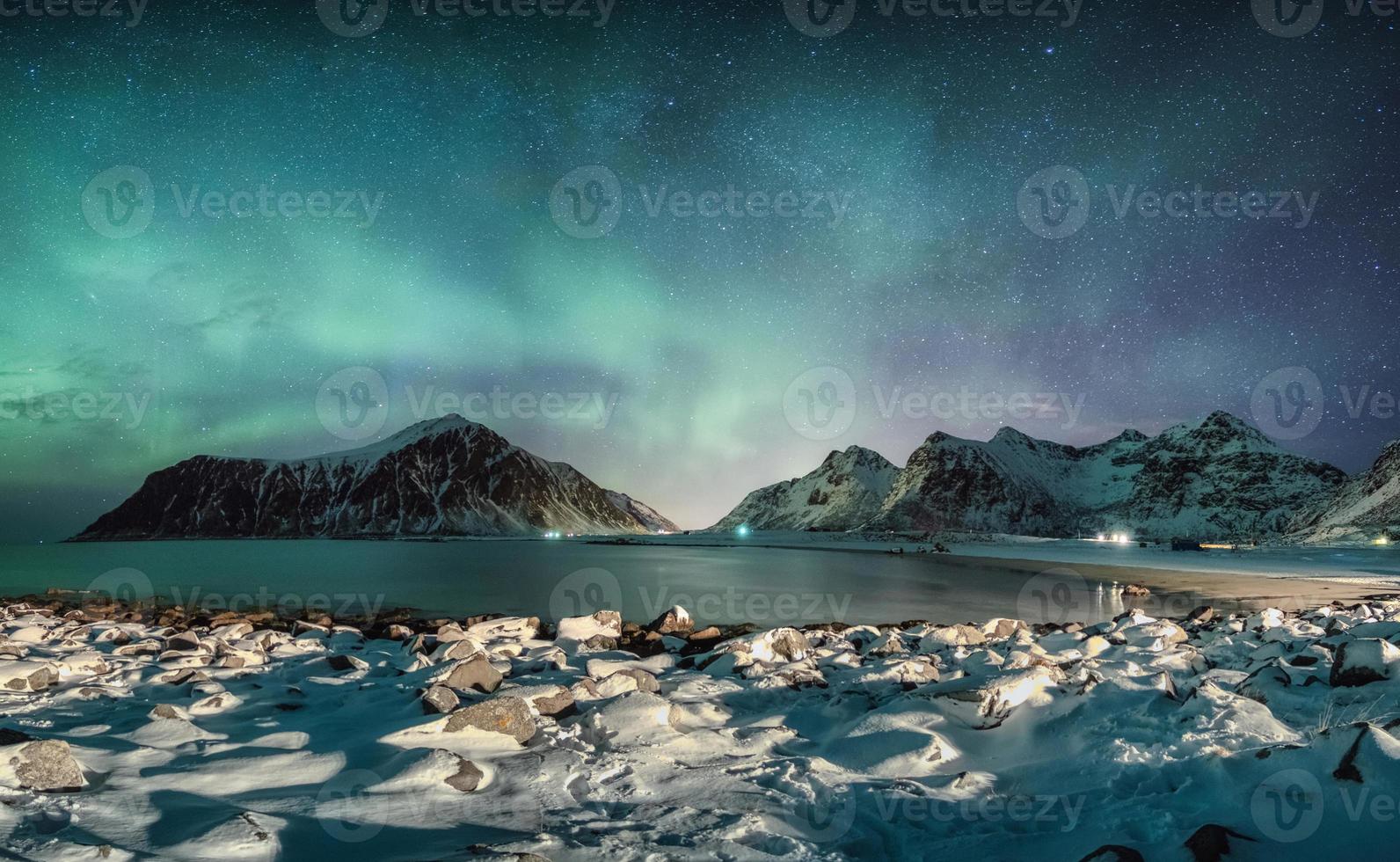 aurora boreale con stelle sulla catena montuosa con costa innevata sulla spiaggia di skagsanden foto