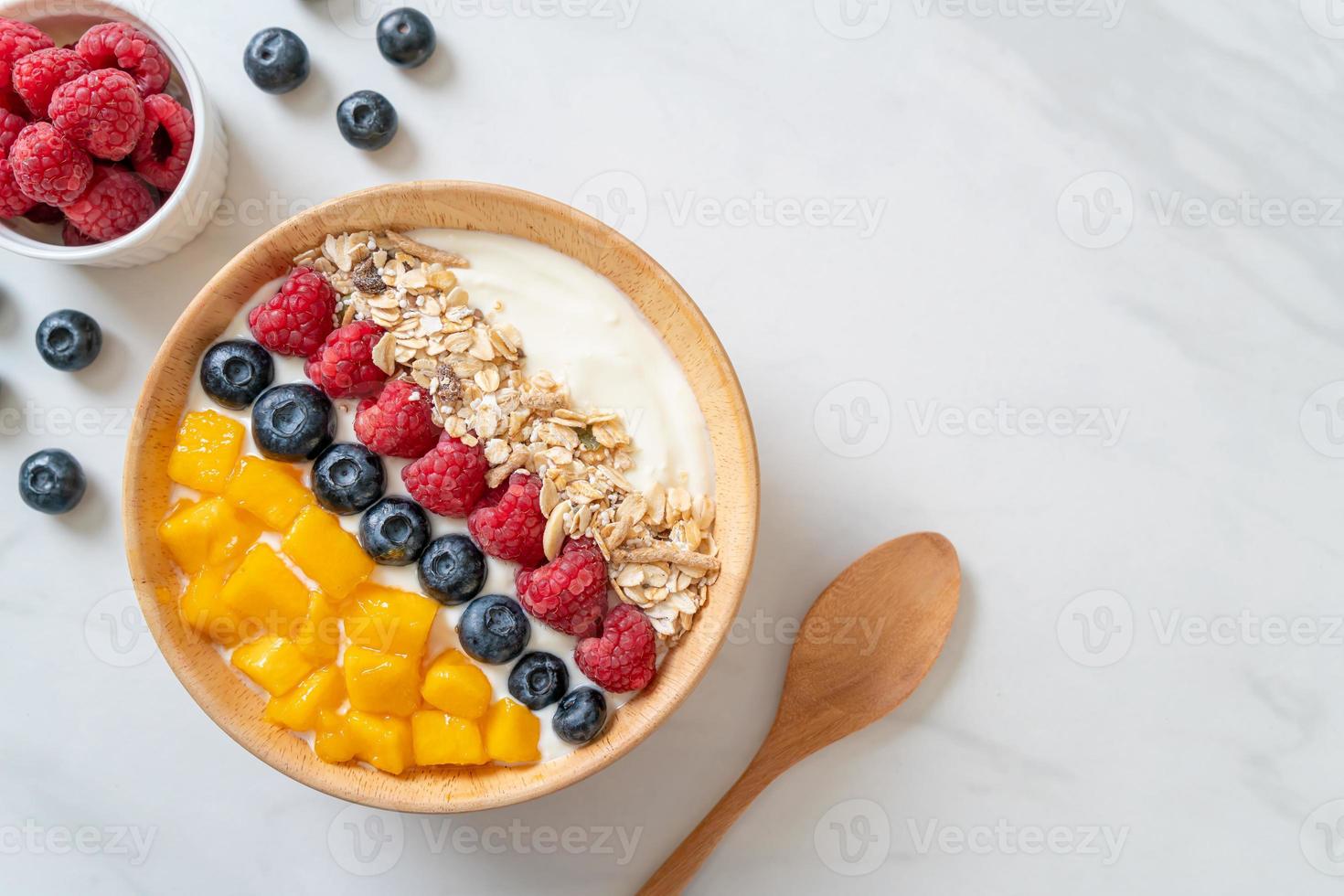 ciotola di yogurt fatta in casa con lampone, mirtillo, mango e muesli - stile alimentare sano foto